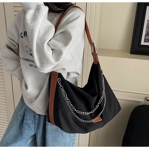 Détail du sac hobo en nylon noir avec bandoulière en cuir marron et chaîne argentée
