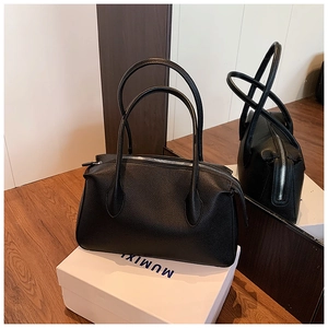 Dettaglio borsa tote nera in pelle martellata con zip argentata e lunghi manici a spalla