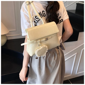 Detail of cream leather backpack with pleats, lace heart charm and flap closure