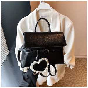 Macro view of black glossy PU leather handbag with a vintage lace heart charm detail