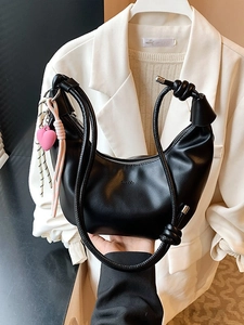 Bolso medialuna negro minimalista con correa anudada y detalle de colgante corazón