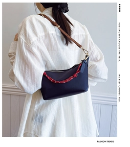 Detail view of navy canvas shoulder bag with brown leather strap and woven decorative cord