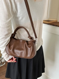 Minimalist pleated cloud crossbody bag in dark brown leather worn by model