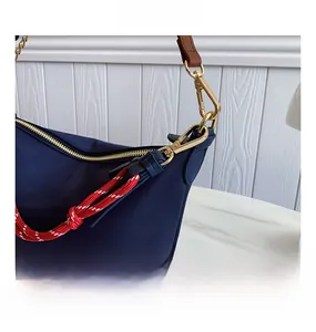 Detail of navy blue nylon bag featuring gold metal hooks and red-white braided rope cord