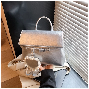 Detail view of silver metallic crinkle bag with heart charm and white lace trim