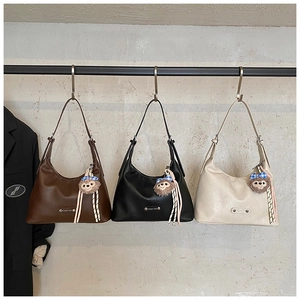 Three minimalist underarm bags in brown, black, and white with cute plush pendants