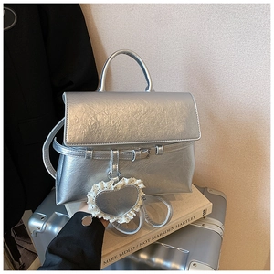 Detail of silver metallic handbag with vintage crinkle texture and lace heart charm