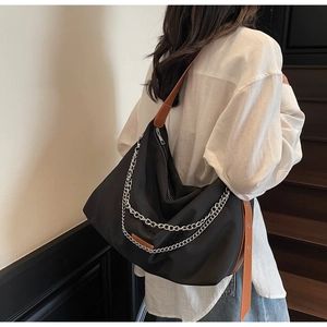 Detail of a black large nylon tote bag with silver chains and brown leather straps