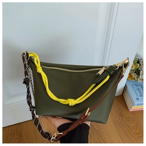 Close-up of olive green crossbody bag with yellow rope handle and patterned strap