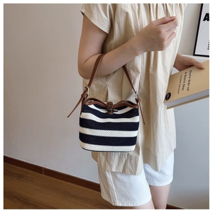 Detail of striped crochet bucket bag with brown leather handle and wooden toggle closure