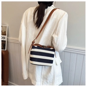 Detail of striped crochet shoulder bag with brown leather strap and wooden buckle