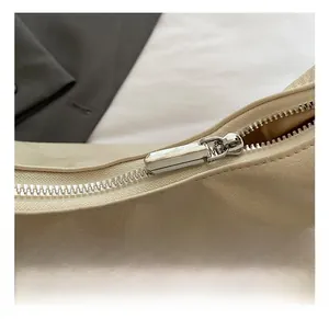 Detail of silver metal zipper and beige lychee texture leather on shoulder bag