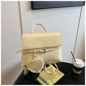 Detail view of cream beige PU leather backpack with a decorative lace heart charm