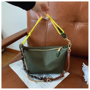 Detail of dark green canvas bag with yellow rope handle and gold metal zipper closure