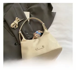 Detail of cream shoulder bag with wrinkled faux leather texture and plush bear charm