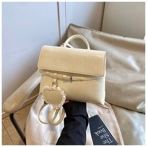 Detail of cream white textured leather handbag with elegant lace heart charm and buckle