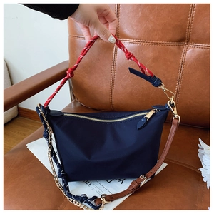 Detail of dark blue nylon bag featuring tri-strap system with gold-tone hardware on leather