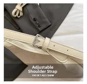 Detail of adjustable shoulder strap with silver buckle on cream minimalist underarm bag