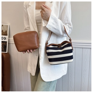 Detail showing woven black and white striped shoulder bag with brown leather trim