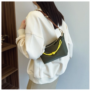 Detail of dark green canvas shoulder bag featuring bright yellow rope handle and zip