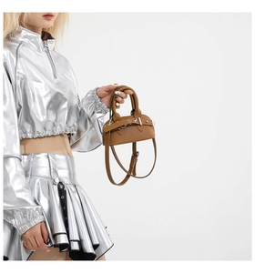 Detail view of brown lychee grain leather shell bag with adjustable belt and long strap