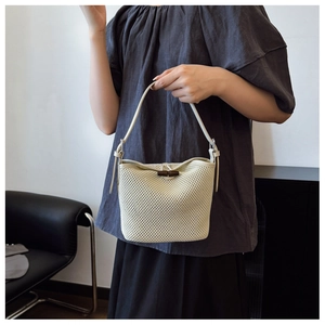 Close-up of woven straw bucket bag with dark wooden toggle clasp and thin leather strap