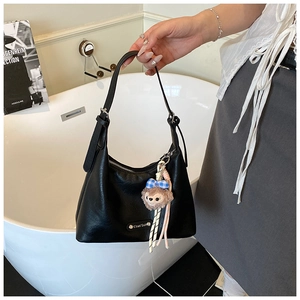 Detail view of black lychee-textured leather bag with a cute plush doll keychain