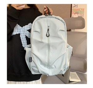 Detail of light blue nylon backpack side pocket with drawstring and brand woven label