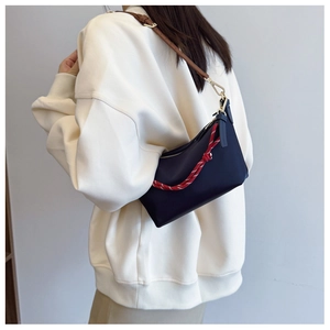 Detail showing deep blue shoulder bag with red decorative rope and brown leather strap
