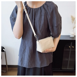 Minimalist beige matte leather shoulder bag with adjustable strap and silver metal buckle
