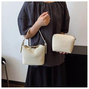 Detail view of woven straw bucket bag set with bamboo buckle and leather inner pouch