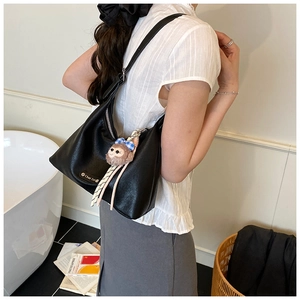 Detail of black matte PU leather hobo bag with a cute monkey plush charm accessory