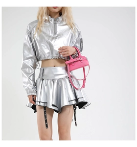 Close-up of a mini bright pink shell-style crossbody bag paired with silver metallic outfit