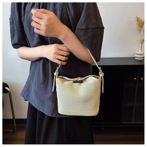 Detail of raffia woven bucket bag featuring a unique bamboo toggle closure and fine texture