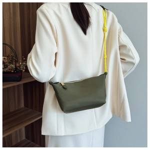 Detail of dark green nylon pleated bag with a bright yellow knotted rope shoulder strap