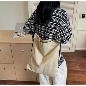 Close-up of beige canvas bucket bag showing natural texture and black shoulder strap