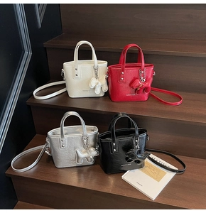 Chic textured bucket bags with cute puppy charms arranged on wooden steps with art book