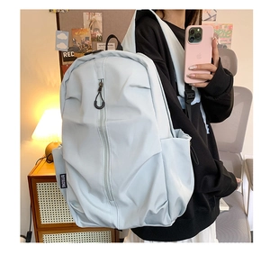 Detailed side view of a light blue minimalist backpack with brand tag in home setting