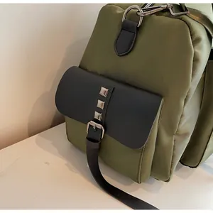 Close-up of military green nylon fabric with silver metal rivets and black leather buckle