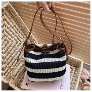 Close-up of raffia woven bucket bag with blue stripes and leather strap detail