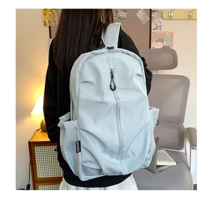 Detail of light blue waterproof nylon backpack featuring side pockets and woven brand label