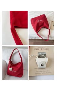 Detail of red canvas tote bag with contrast C'est la vie text and mini pouch accessory