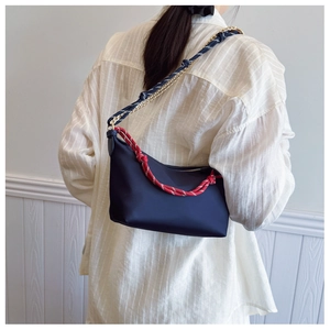 Detail of dark blue nylon shoulder bag with red-white rope and gold chain strap