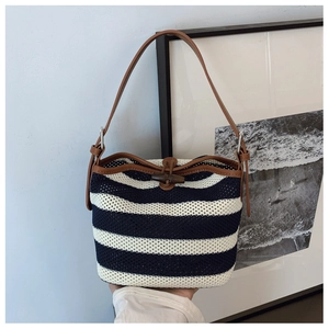 Detail of nautical striped knit bucket bag with brown leather trim and wooden horn button