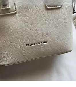 Close-up of cream bucket bag showing natural faux leather texture and brand lettering