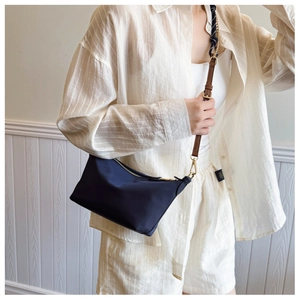 Detail of navy blue canvas bag with elegant silk scarf handle and gold zipper closure