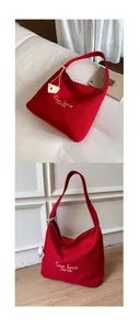 Detail of red canvas tote bag featuring white embroidery and leather heart charm