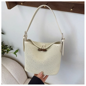 Detail of cream woven shoulder bag featuring a dark brown wooden horn toggle closure