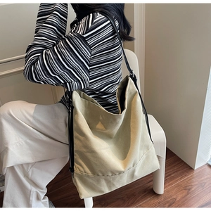 Detailed view of a large beige canvas bucket bag worn by a model in a minimalist setting