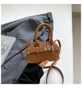 Close-up of a brown litchi pattern mini shell bag with retro belt buckle details